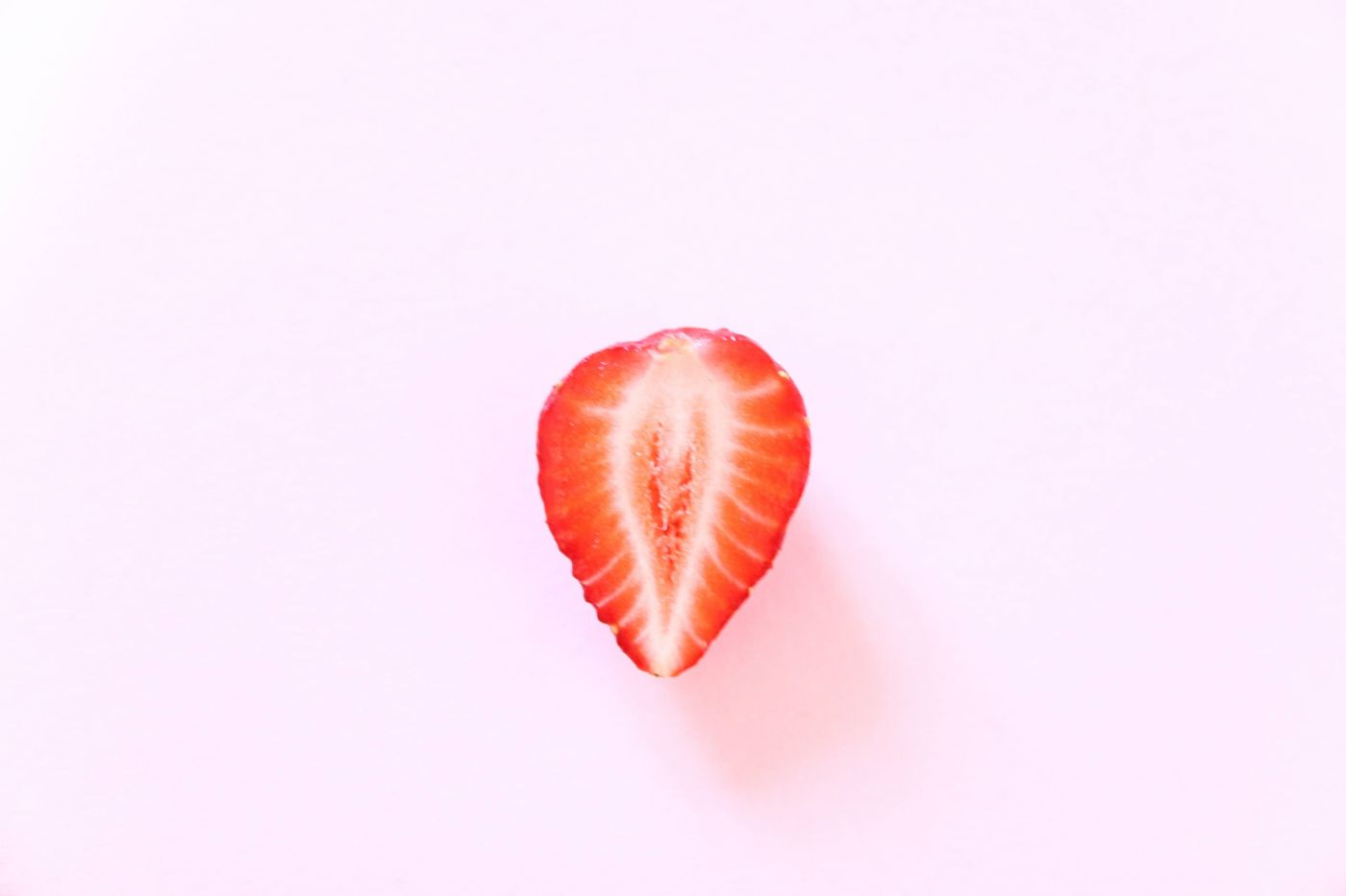 A halved strawberry on a soft pink background